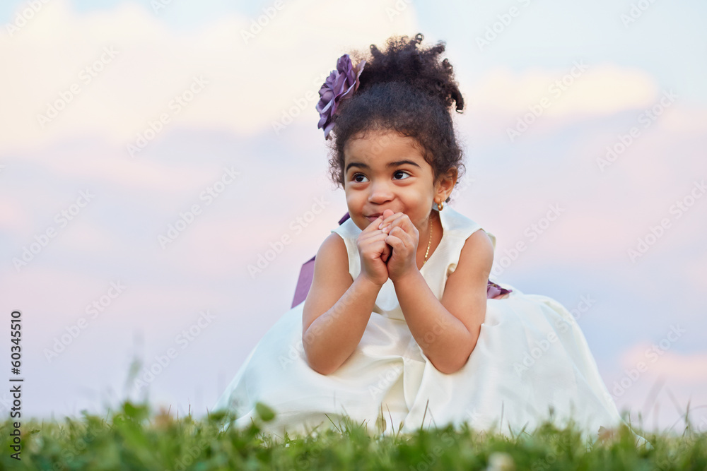 Little smiling girl in beautiful gown sits squatteg on meadow Little smiling girl in beautiful gown sits squatteg on meadow