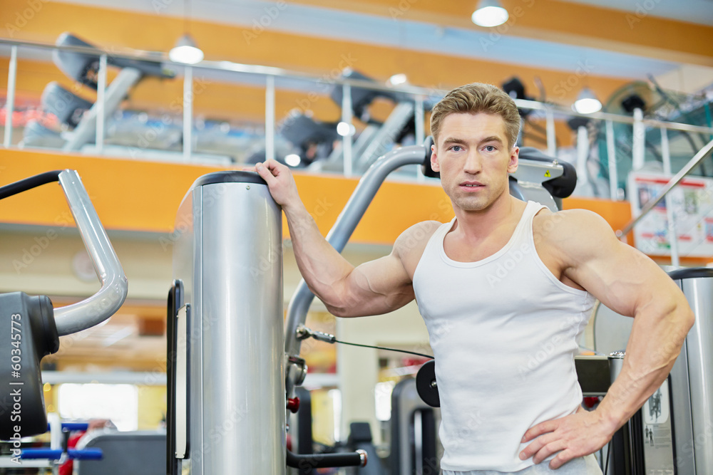 Bodybuilder stands leaning on traineger in gym hall Bodybuilder stands leaning on traineger in gym hall