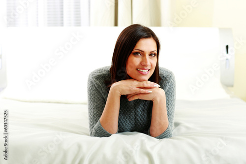 Middle-aged happy smiling woman lying on the bed at home