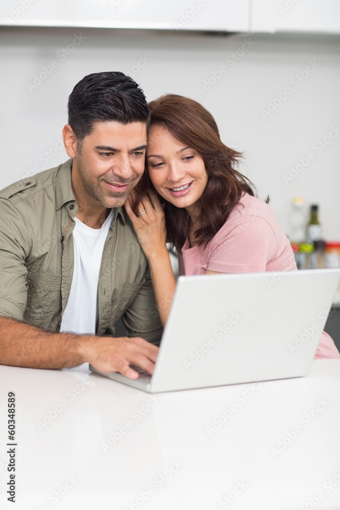 Happy couple using laptop in kitchen Happy couple using laptop in kitchen