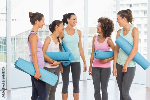Fit smiling young women with exercise mats