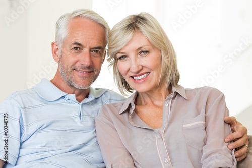 Smiling mature couple sitting on sofa with arm around