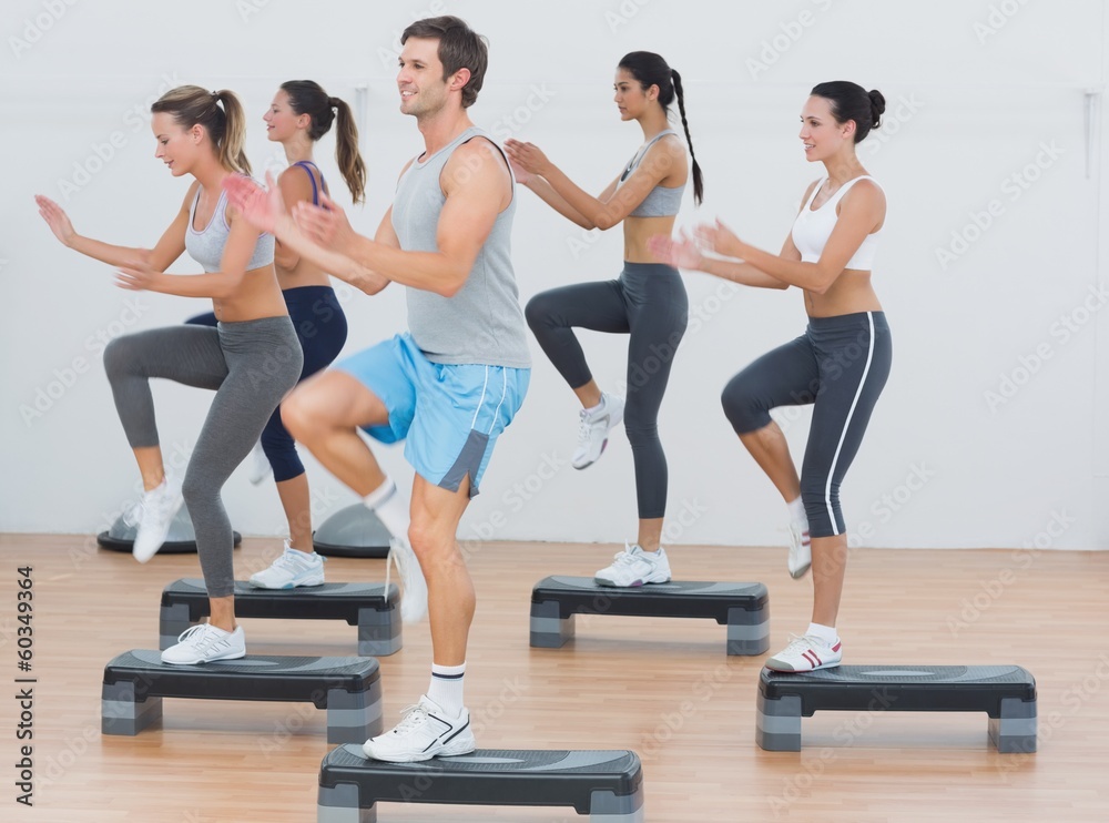 Fitness class performing step aerobics exercise Fitness class performing step aerobics exercise
