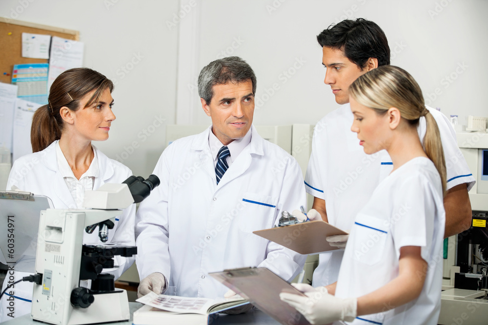 Scientist With Students Taking Notes In Laboratory Scientist With Students Taking Notes In Laboratory