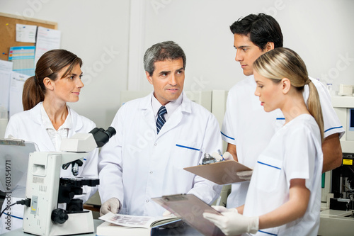 Scientist With Students Taking Notes In Laboratory