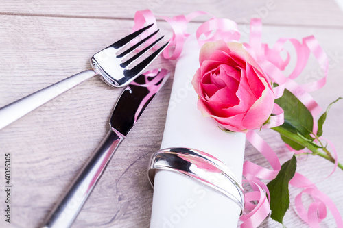 romantisch gedeckter tisch mit silberbesteck und einer rose