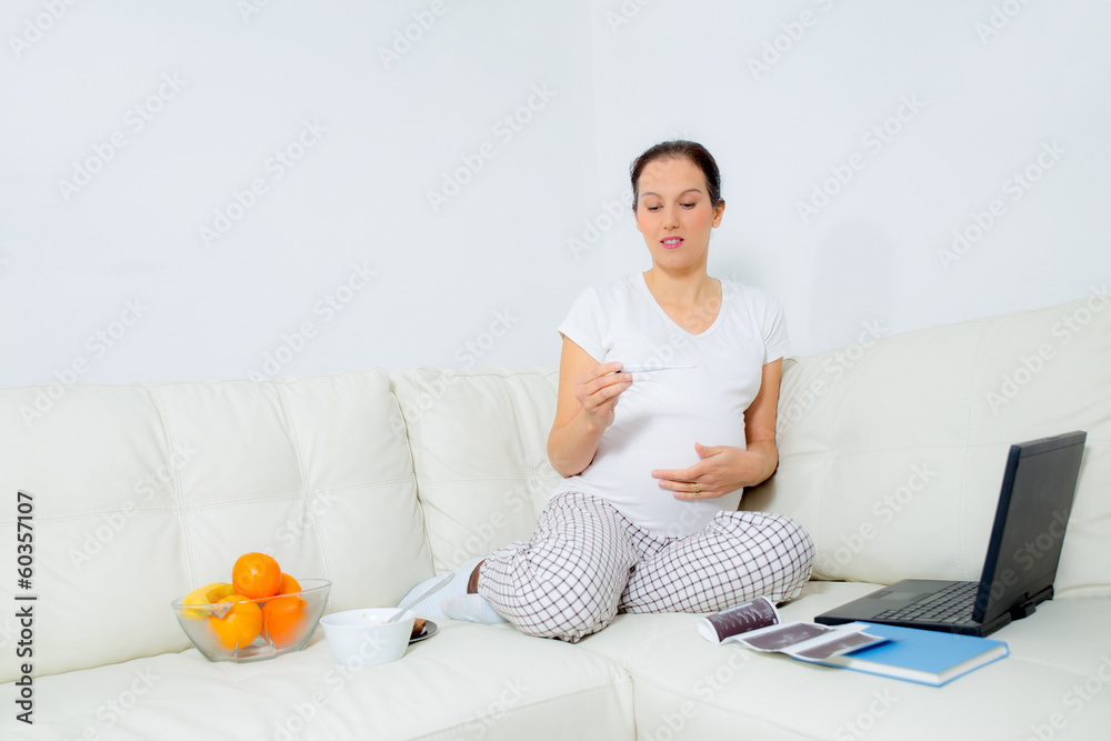 pregnant woman measuring temperature on sofa at home pregnant woman measuring temperature on sofa at home