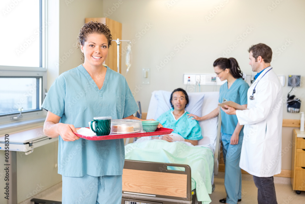 Obraz premium Nurse Holding Tray With Medical Team And Patient In Background