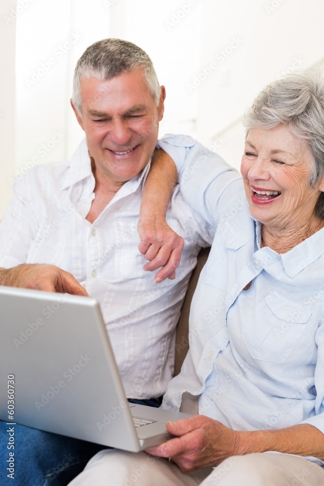 Happy senior couple looking at laptop