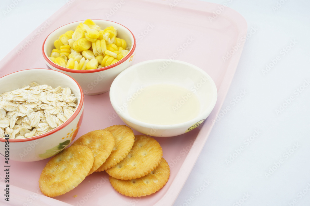 Corn, oats, cracker and sweetened condensed milk on pink tray Corn, oats, cracker and sweetened condensed milk on pink tray
