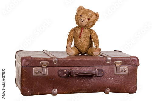 old teddybear sitting on suitcase