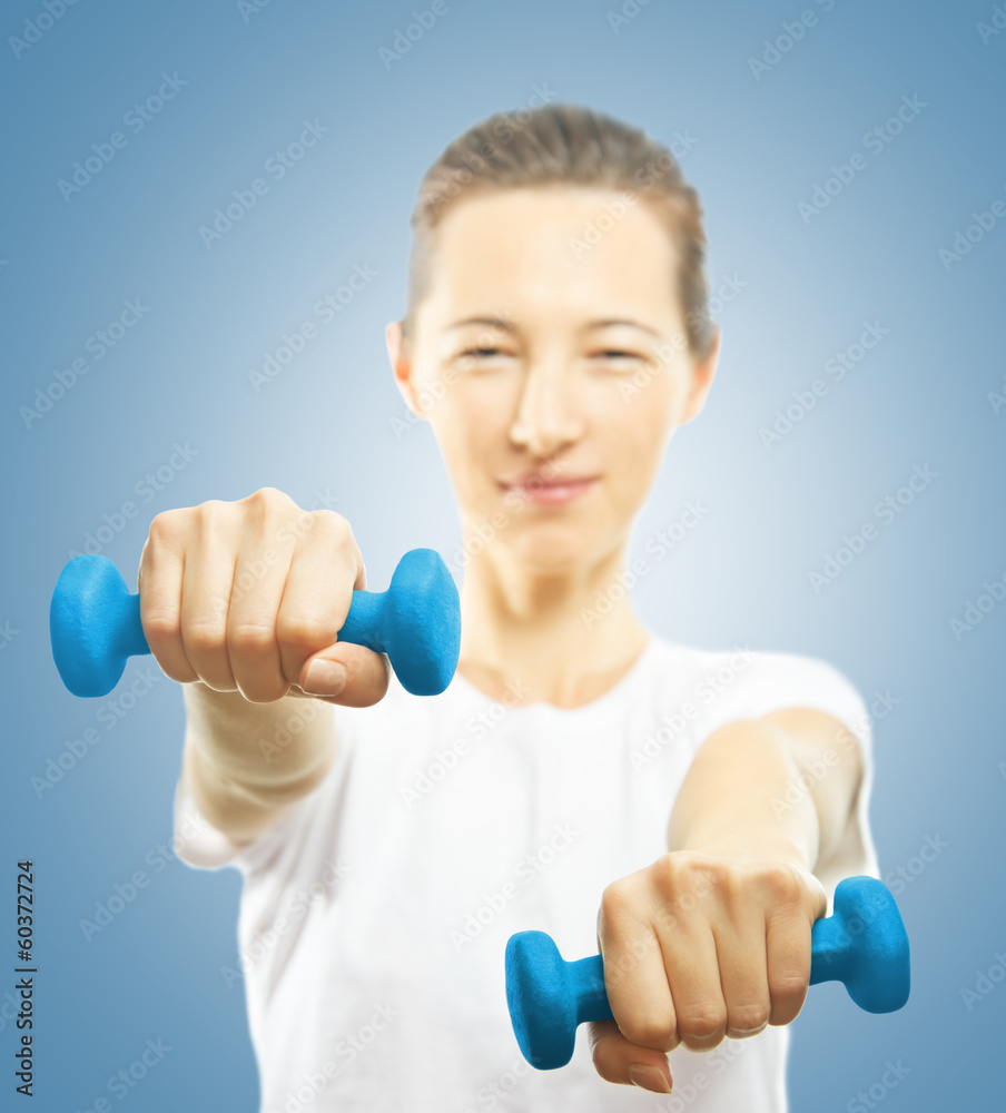 Young woman with dumbbells, focus on the dumbbell Young woman with dumbbells, focus on the dumbbell