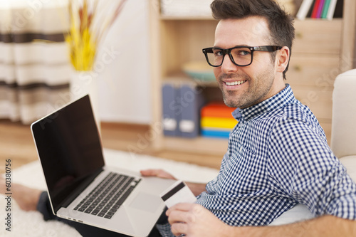 Happy man with laptop and credit card at home