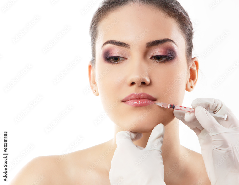 Young woman receiving cosmetic lip injection with syringe
