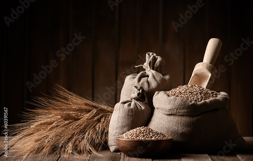 Canvas Print Grains of wheat in bags and ears on a wooden platform