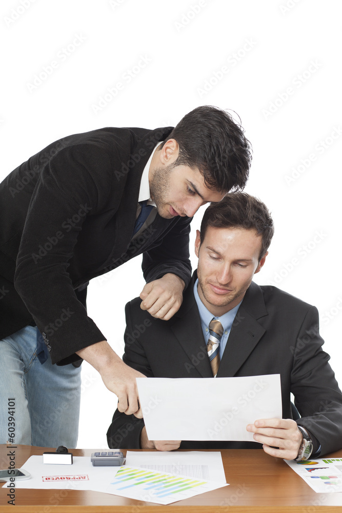 Two businessmen using paper at desk in office Two businessmen using paper at desk in office