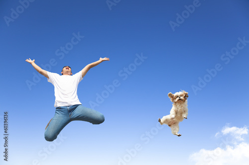 Fototapeta young man and dog jumping in the sky