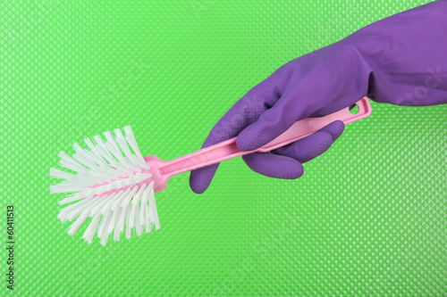 Toilet brush in hand on green background