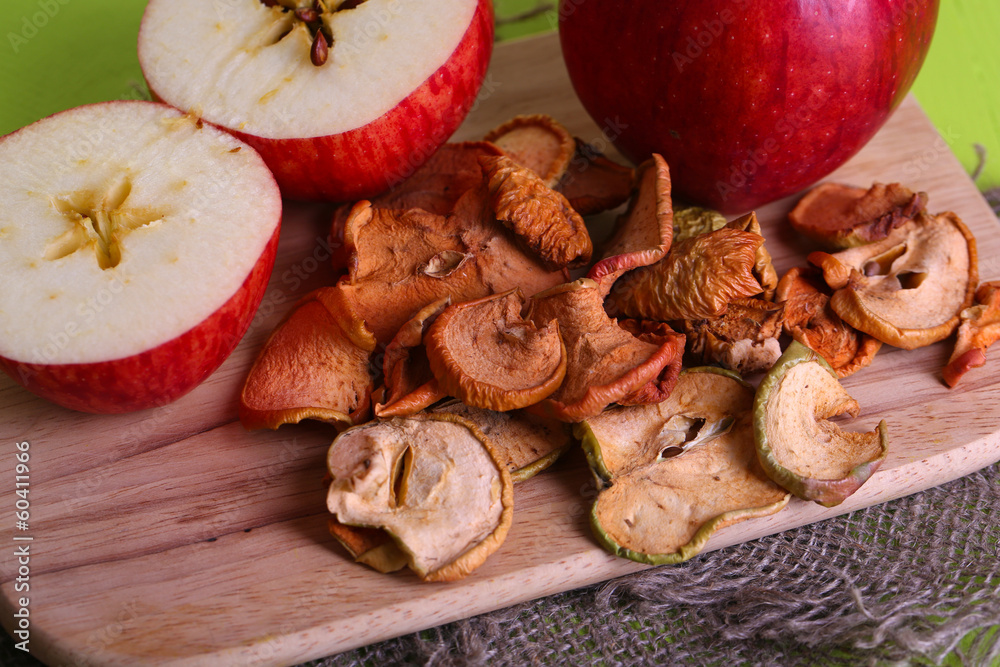 Dried apples, on cutting board, on color wooden background Dried apples, on cutting board, on color wooden background