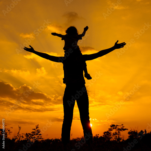 silhouette of a mother and son who play outdoors at sunset backg