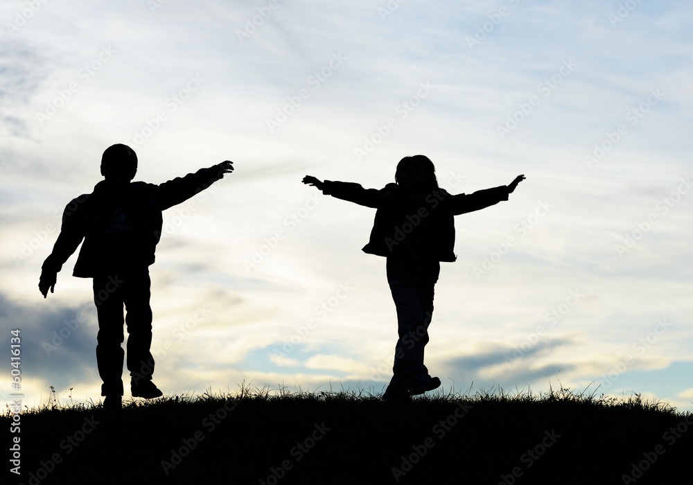 Happy children silhouettes playing in park