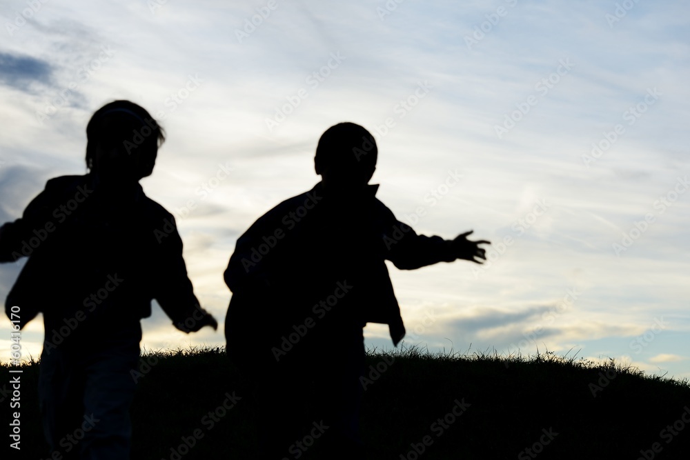 Happy children silhouettes playing in park