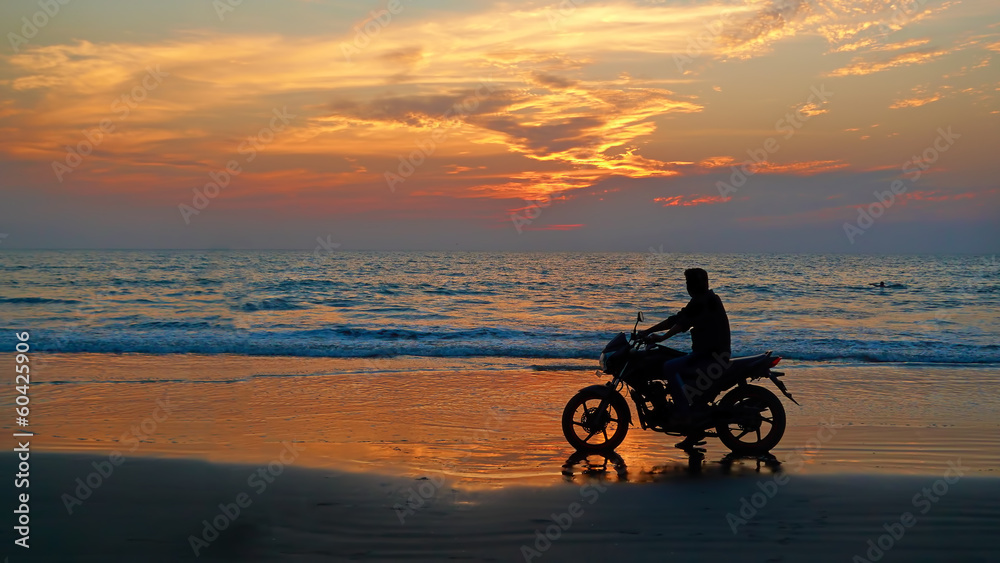 Fototapeta premium Motorcyclist at sunset on the beach. Abstract background 