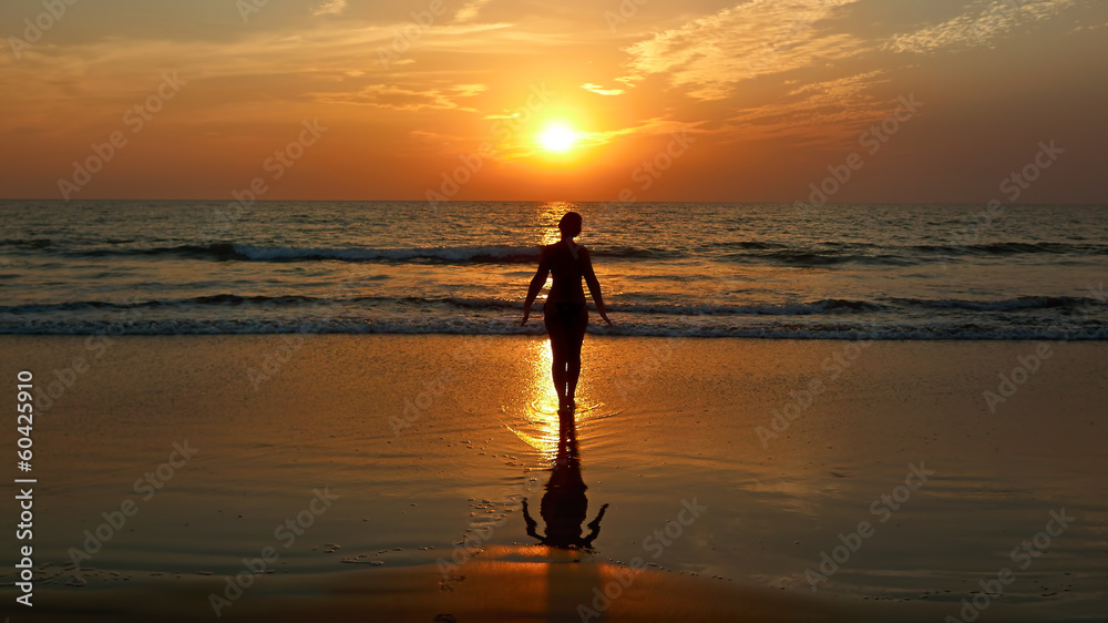 Girl doing yoga at sunset on the beach.