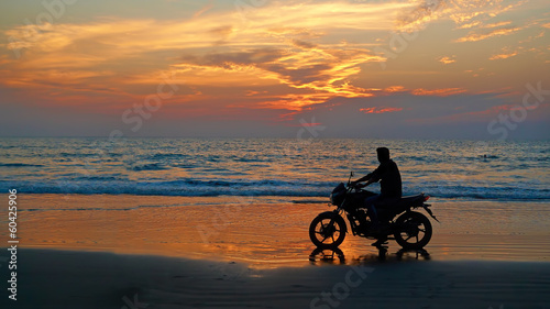 Motorcyclist at sunset on the beach. Abstract background "lifest