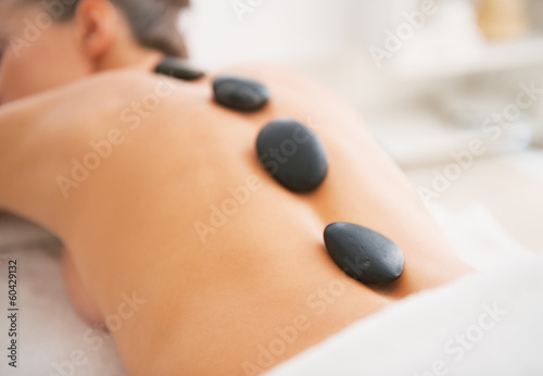 Closeup on young woman receiving hot stone massage. rear view