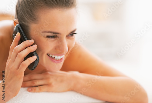 Portrait of woman laying on massage table and talking cell phone