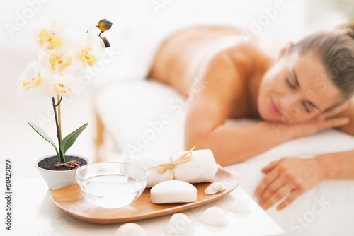 Closeup on spa therapy ingredients and young woman in background