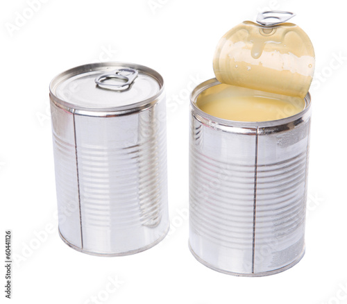 Condensed milk in tin cans over white background photo