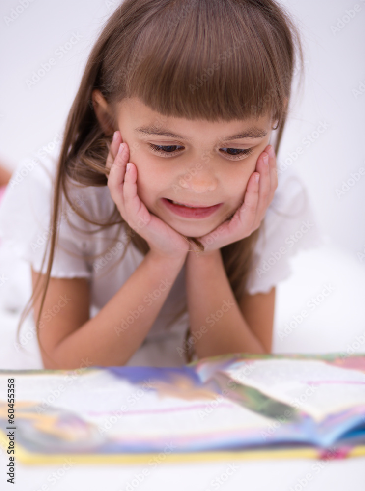 Naklejka premium Little girl is reading a book