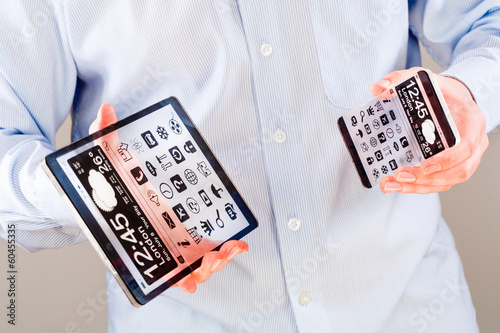 Smartphone and tablet with transparent screen in human hands.