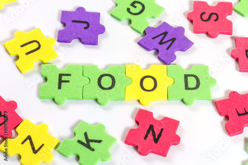 word FOOD formed with colorful foam puzzle on white background