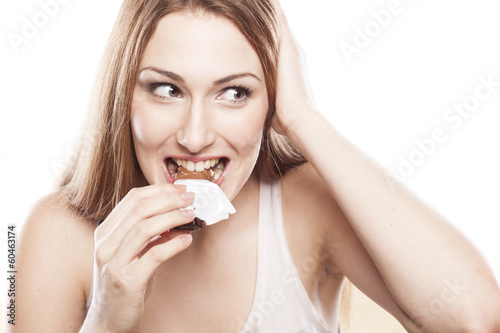 smiling girl eating a chocolate bar on white background
