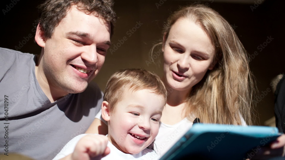 Parents watching son playing game on touchpad