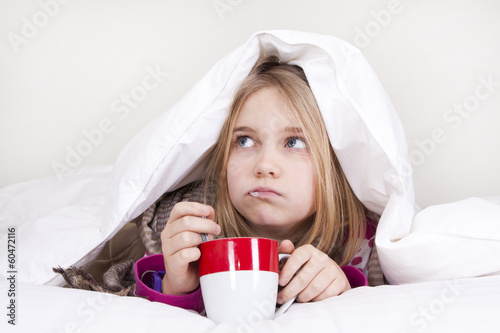 Sick young girl with thermometer in bed