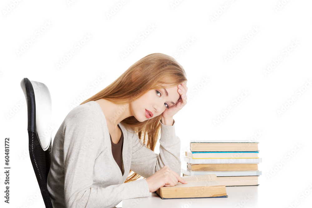 Bored and tired casual student woman sitting by the desk and lea Bored and tired casual student woman sitting by the desk and lea