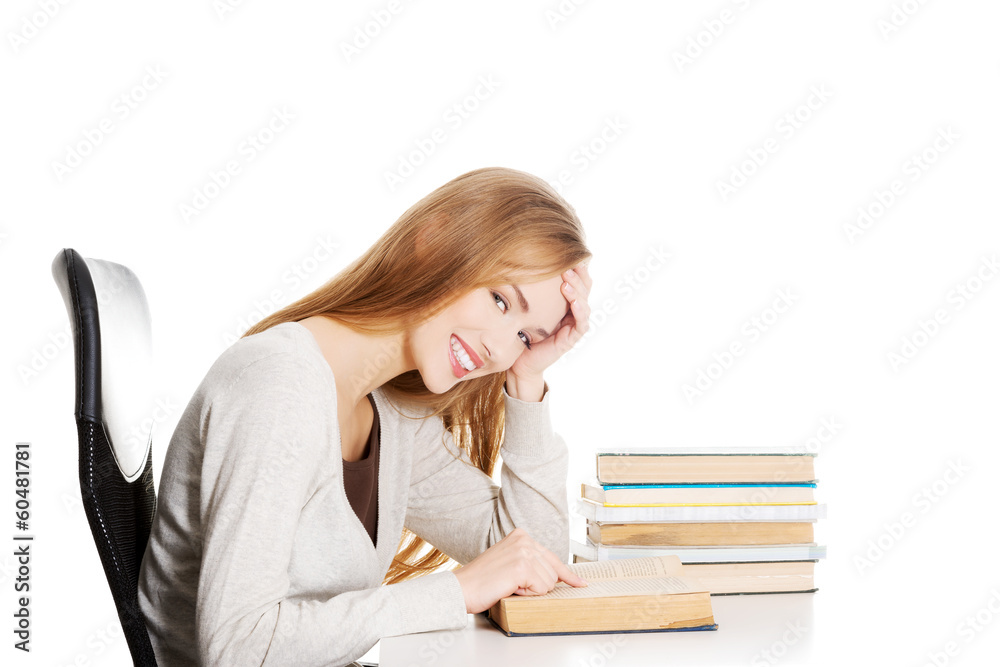 Beautiful student woman sitting by the desk with books and learn Beautiful student woman sitting by the desk with books and learn