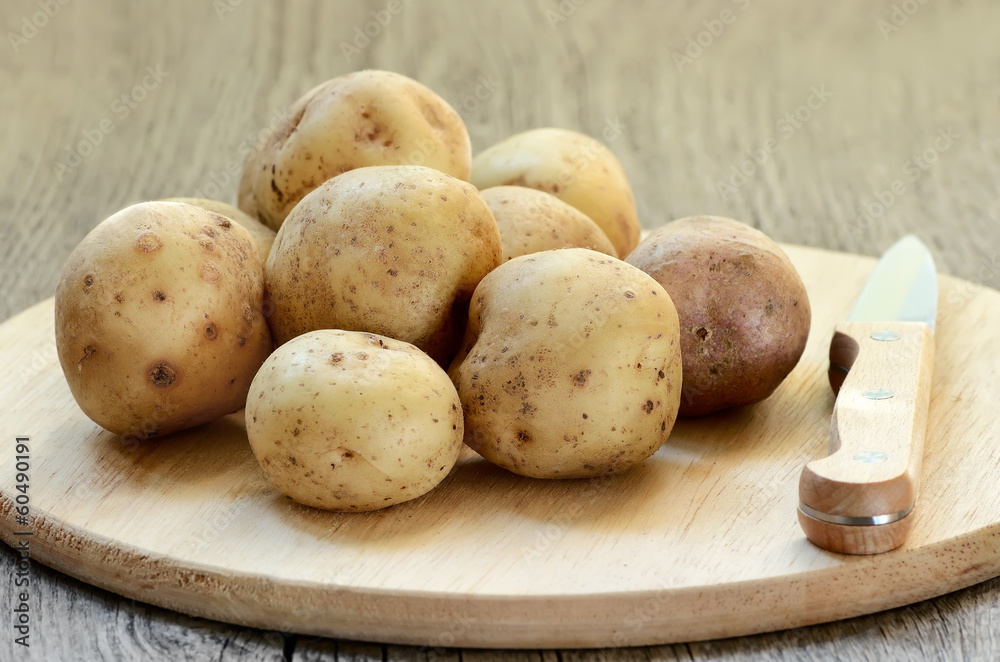 Raw potatoes in bowl on wooden table Raw potatoes in bowl on wooden table