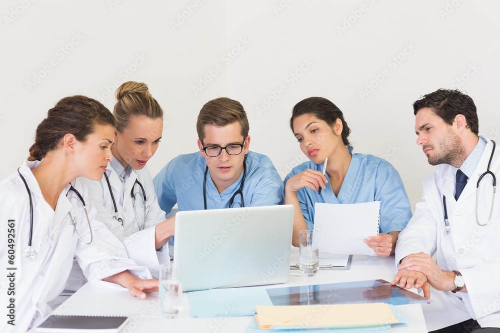 Doctors and nurses discussing over laptop