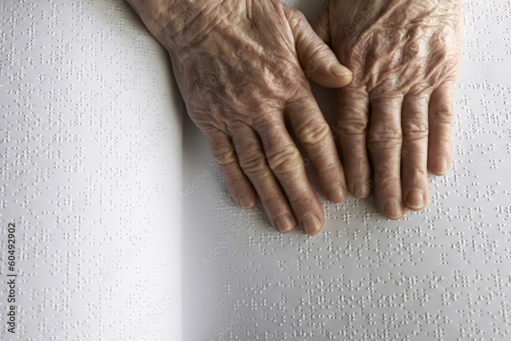 Fototapeta premium Old woman' s hands, reading a book with braille language