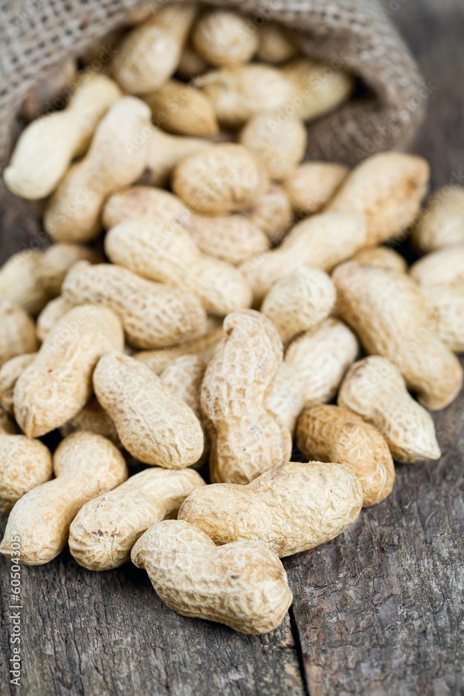 peanuts in a miniature burlap bag on wooden surface peanuts in a miniature burlap bag on wooden surface