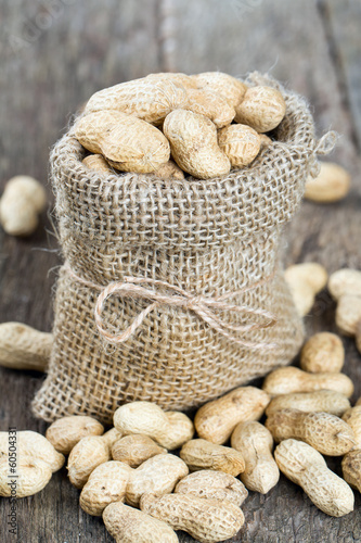 peanuts in a miniature burlap bag on wooden surface