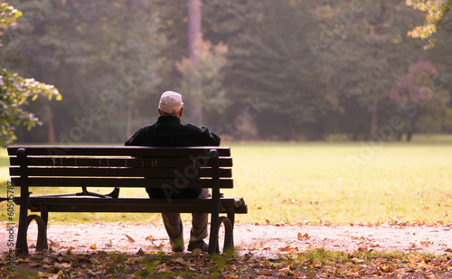 Old man sitting on a bench in autumn, autumn of life photo
