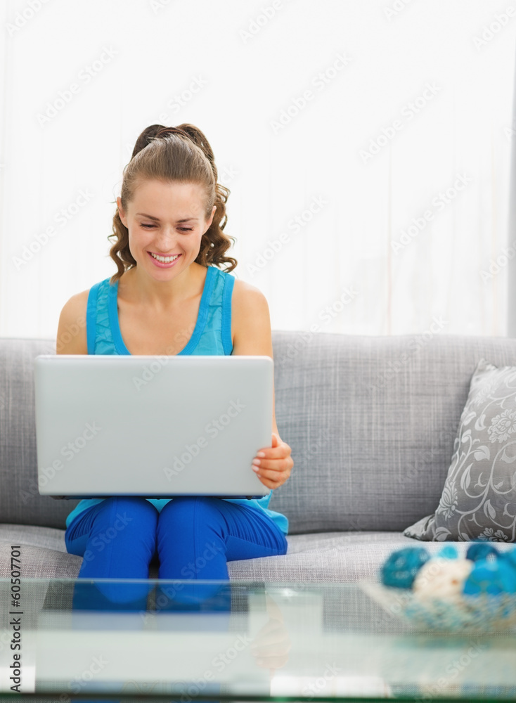 Happy young woman sitting in living room and using laptop Happy young woman sitting in living room and using laptop