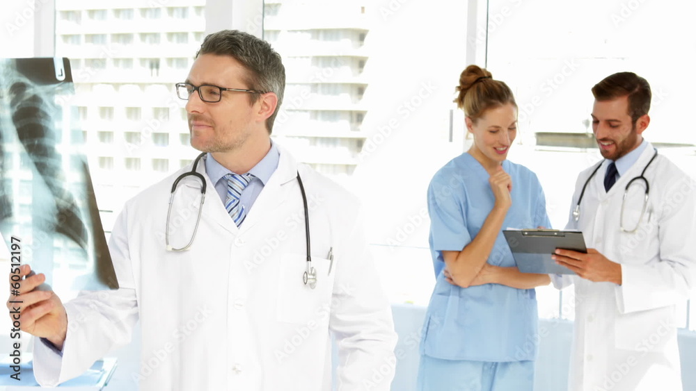 Doctor looking at xray then smiling at camera Doctor looking at xray then smiling at camera