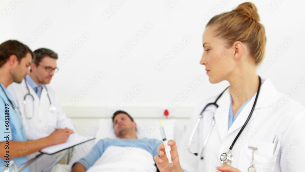 Doctors speaking with sick patient while nurse prepares needle Doctors speaking with sick patient while nurse prepares needle